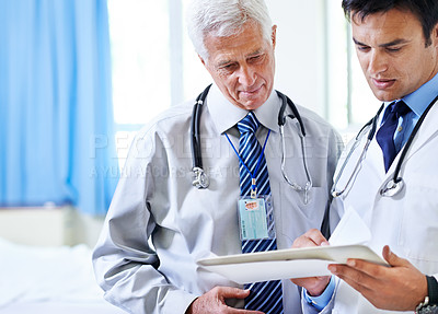 Buy stock photo Shot of two doctors discussing a case file