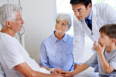 Buy stock photo Shot of a sick man in a hospital bed getting news from his doctor while his family visits