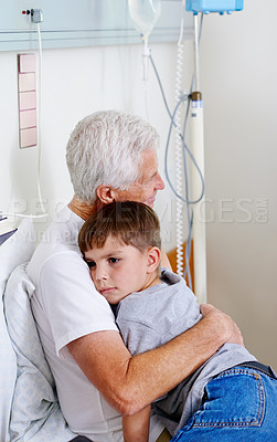 Buy stock photo Shot of a sick man in a hospital bed getting a hug from his grandson