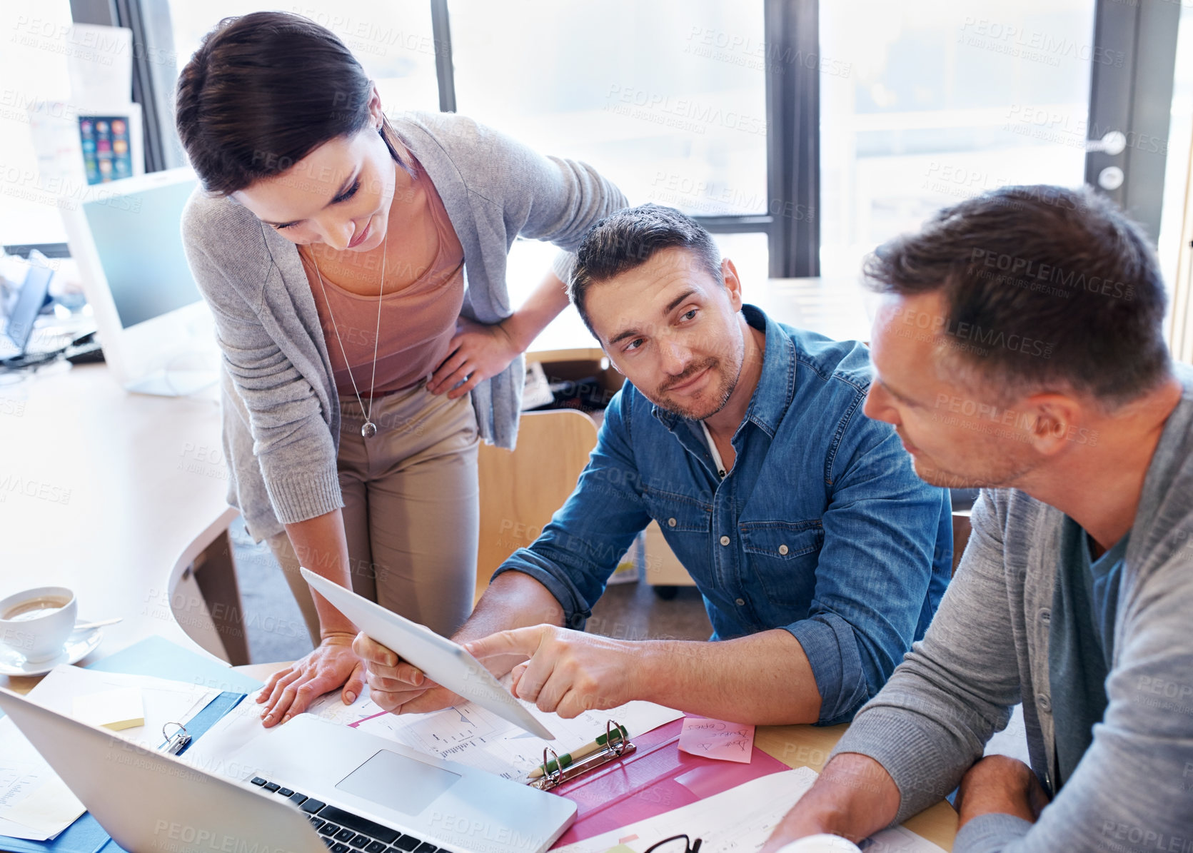 Buy stock photo Shot of three coworkers using a tablet in a discussion