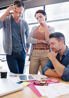 Buy stock photo Shot of three coworkers considering a problem together