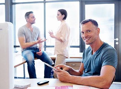 Buy stock photo Portrait of an office worker using a tablet while his coworkers have a discussion in the background