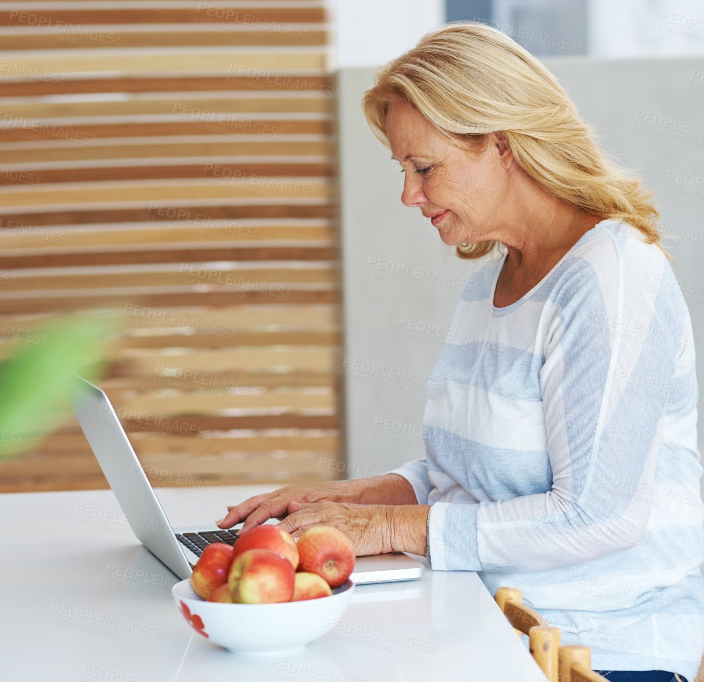 Buy stock photo Laptop, smile and typing with senior woman in kitchen of home for browsing internet or research. Computer, remote work and trading for passive income with elderly person in apartment to freelance