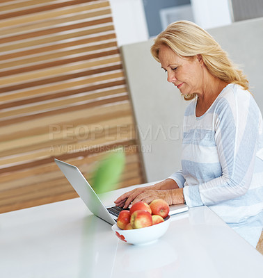 Buy stock photo Laptop, remote work and typing with senior woman in kitchen of home for browsing internet or research. Apples, computer and trading for passive income with elderly person in apartment to freelance