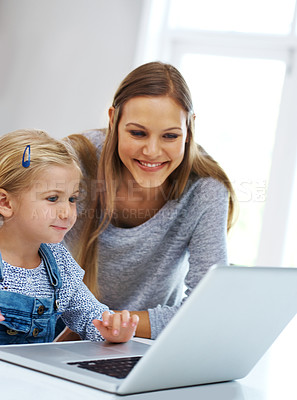 Buy stock photo Shot of a happy mother helping her little girl with the laptop