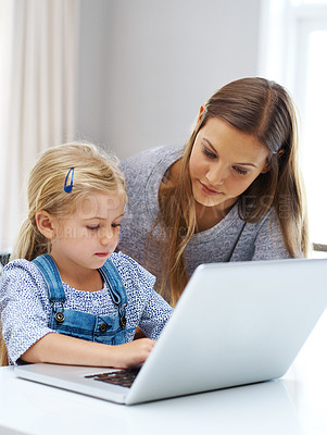Buy stock photo Shot of a young mother helping her little girl with the laptop