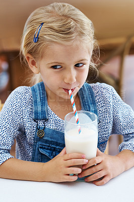 Buy stock photo Girl, child and drinking milk in home, thinking and vitamin d liquid for growth development. Female person, kid and glass of mineral juice for calcium at kitchen table, dairy breakfast and pondering