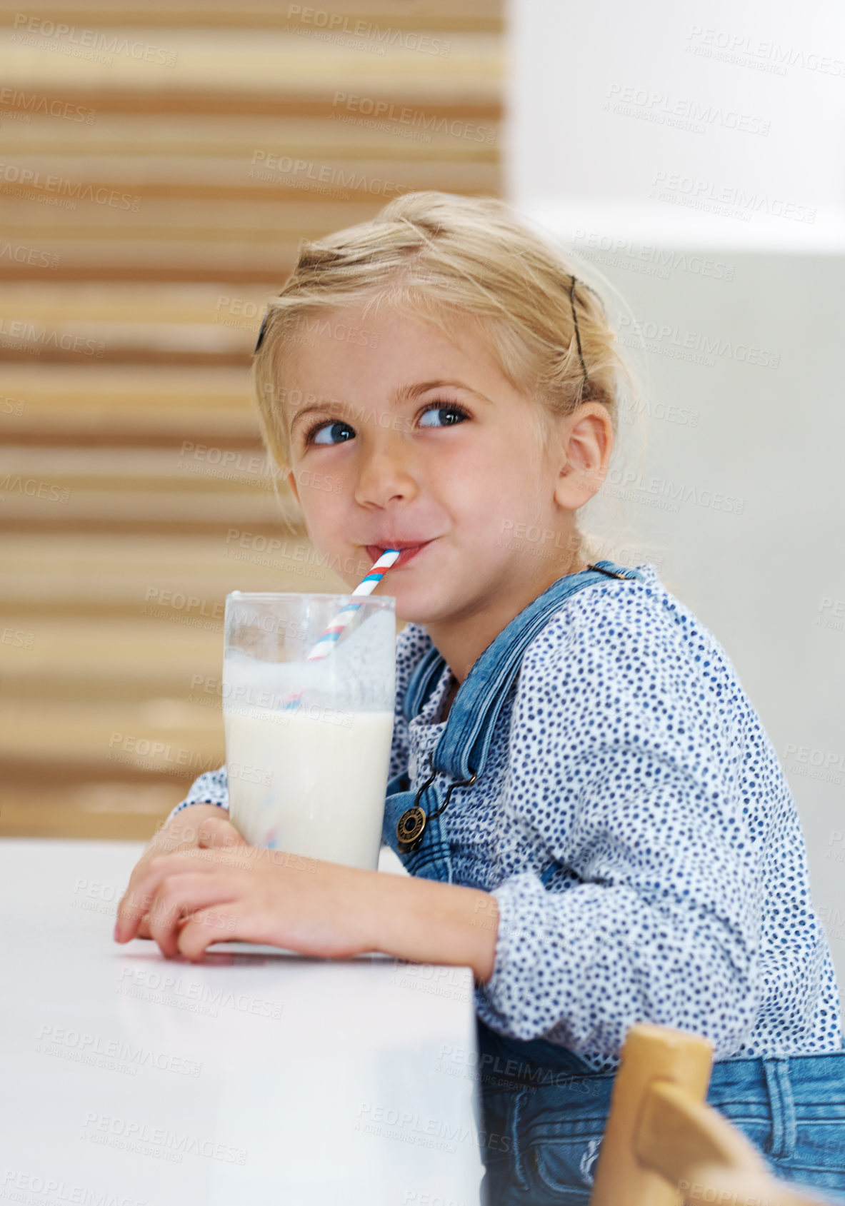 Buy stock photo Girl, child and drinking milk in home, food thought and vitamin d liquid for growth development. Female person, kid and glass of mineral calcium support at kitchen table, dairy breakfast and daydream