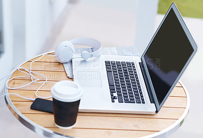 Buy stock photo A modern laptop with headset a coffee cup and cellphone outside on a table at an internet cafe. An open computer screen with a smartphone device for freelance work or remote setup at a restaurant