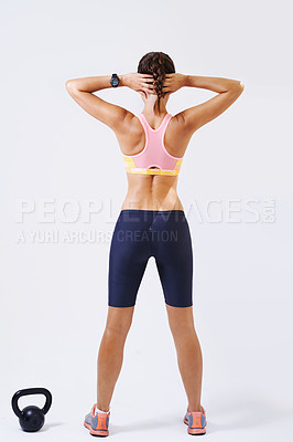 Buy stock photo Rearview shot of an attractive young woman stretching for a weight lifting workout