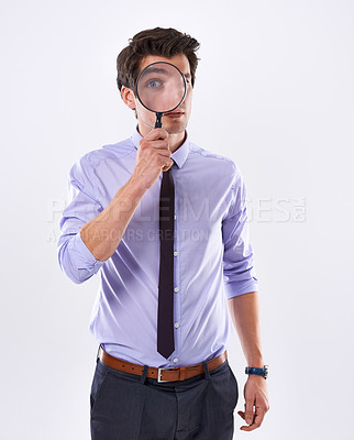 Buy stock photo Studio shot of a young businessman against a white background looking through a magnifying glass