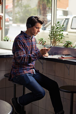 Buy stock photo Texting, man and mobile phone with headphones in cafe for podcast, notes or creativity as design student. Male person, education and technology for connection, email or study in university or college