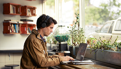 Buy stock photo Learning, headphones and man in cafe on laptop for course, college research or music streaming platform. Male student, coffee shop or typing on technology with online network, connection or study app