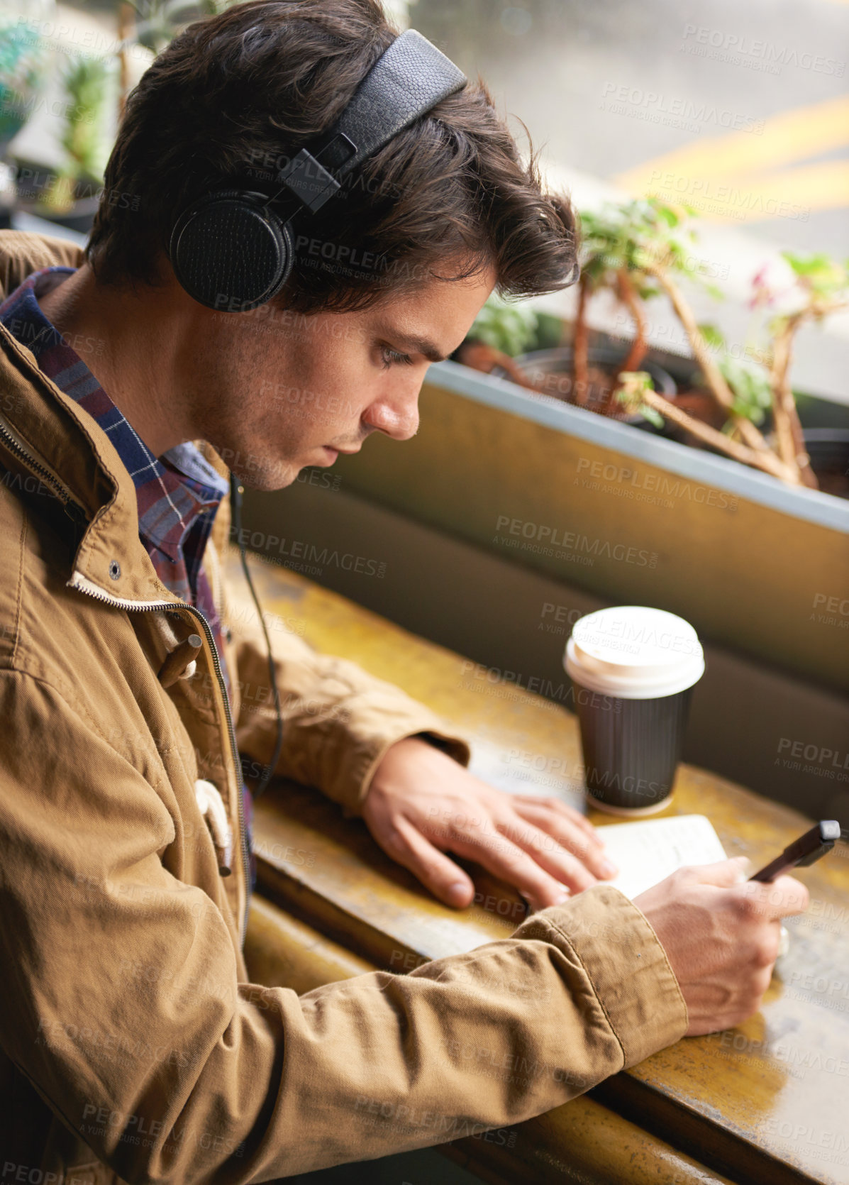 Buy stock photo Student, headphones and coffee in cafe with notebook for study, planning and writing in journal or diary. Man, morning and tea in restaurant with book and streaming for notes, brainstorming and music