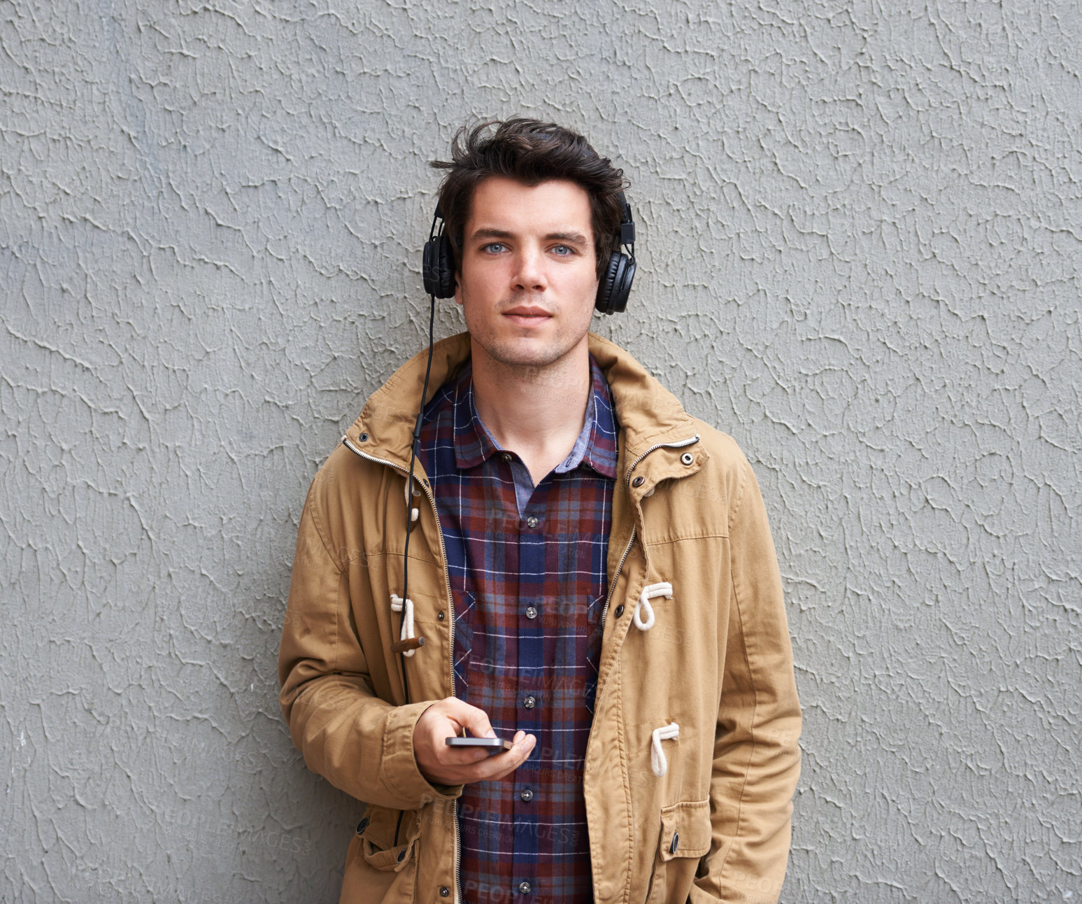 Buy stock photo Man, fashion and portrait at wall with headphones, phone and relax on sidewalk. Student, streetwear and mobile with music for streaming app, podcast and favorite playlist on commute in New York