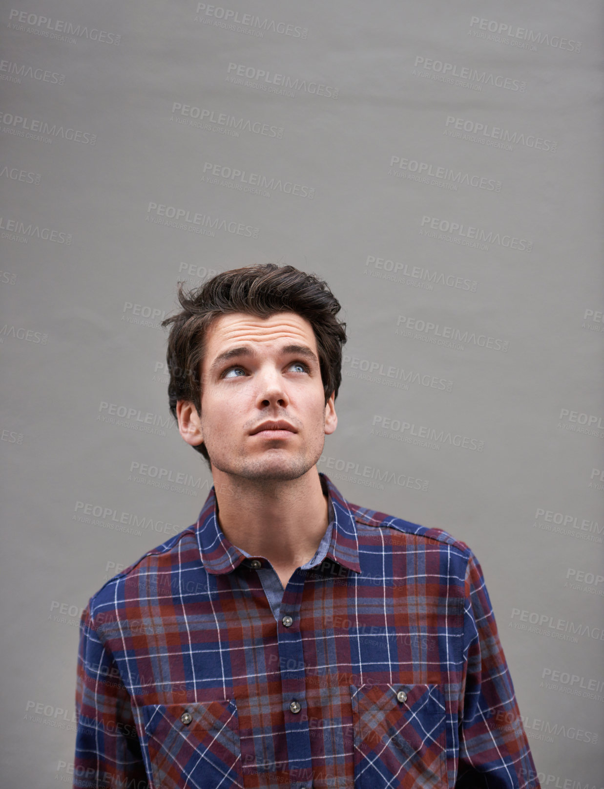 Buy stock photo Cropped shot of a young man standing outdoors and looking up to towards the sky 