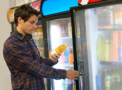 Buy stock photo Cropped shot of a young man reading the ingredients on the back of a juice bottle 