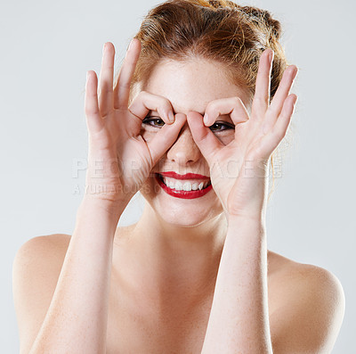 Buy stock photo Studio shot of a beautiful young woman looking at the camera through her fingers