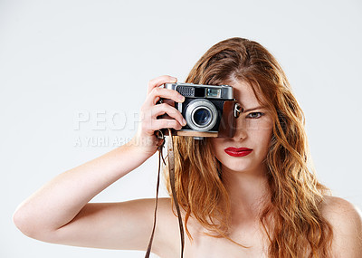 Buy stock photo Studio shot of a beautiful young woman holding a vintage camera in front of her face