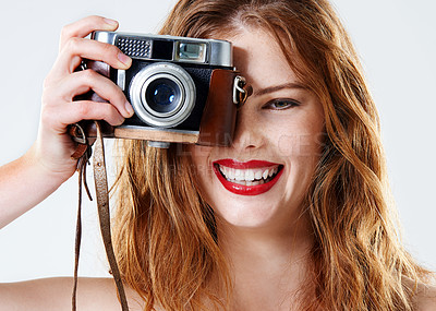 Buy stock photo Studio shot of a beautiful young woman holding a vintage camera in front of her face