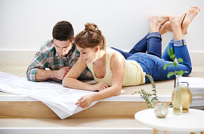 Buy stock photo Shot of a young couple inspecting the building plans for their new home
