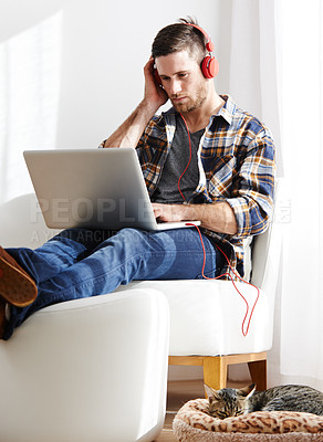 Buy stock photo Man, serious and cat on laptop with headphones for editing videos as videographer with remote work. Male person, pet and concentration as freelancer for audio, music and streaming service at home