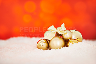 Buy stock photo Studio shot of an arrangement of golden Christmas decorations against a red background