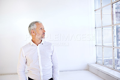 Buy stock photo Shot of a handsome mature businessman looking thoughtful while standing by a window