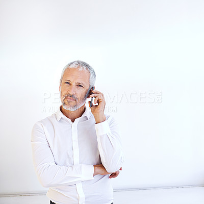 Buy stock photo Portrait of a handsome mature businessman using his mobile phone indoors