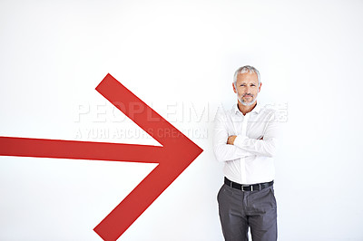 Buy stock photo A mature businessman standing against a white background with a large red arrow pointing at him