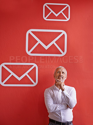 Buy stock photo A mature businessman looking thoughtful while standing against a red background with message symbols