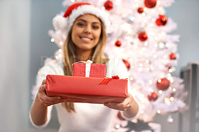 Buy stock photo Portrait of a beautiful young woman holding presents while sitting by a Christmas tree