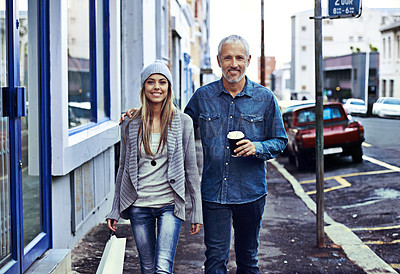 Buy stock photo A beautiful young woman and her father walking with a shopping bag and takeaway coffee in the city