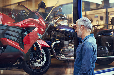 Buy stock photo Shot of a mature man admiring the window display of a motorcycle shop