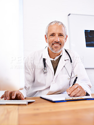 Buy stock photo Portrait of a mature male doctor working at a desktop computer in his office