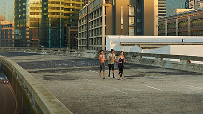Buy stock photo Endurance, friends and running in city for fitness, support and burn calories with exercise as team. Group, people and cardio workout on road for wellness, health benefits and race pace for training
