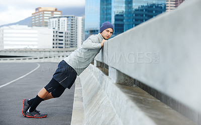 Buy stock photo Shot of a young man warming up for a jog through the quiet city streets