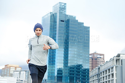 Buy stock photo Cropped shot of a young man jogging through empty city streets