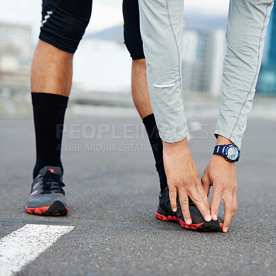 Buy stock photo Cropped shot of a jogger standing on a road stretching 