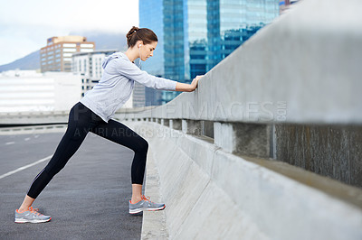 Buy stock photo Shot of a young female jogger stretching on the street before a run