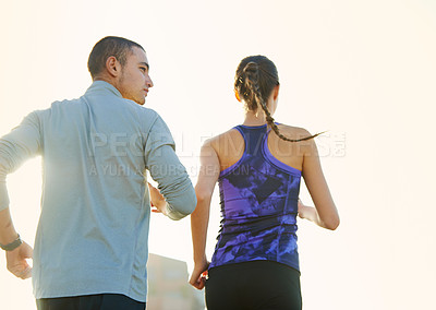 Buy stock photo Rearview shot of two friends jogging through the city