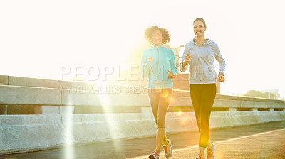 Buy stock photo Women, friends and jogging on road for fitness with training, support and care in California. Workout, exercise and lens flare with running for health, wellness and wellbeing in sportswear in city