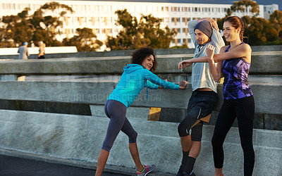 Buy stock photo Shot of three friends stretching at the side of the road before a morning jog