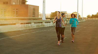 Buy stock photo Shot of three friends out jogging in the city in the early morning