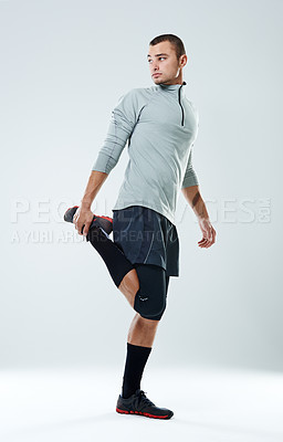 Buy stock photo Full length shot of a young man doing stretches in a studio