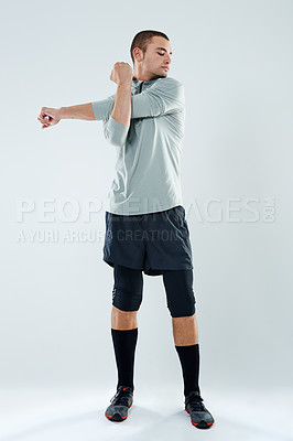 Buy stock photo Shot of a young man doing stretches in a studio