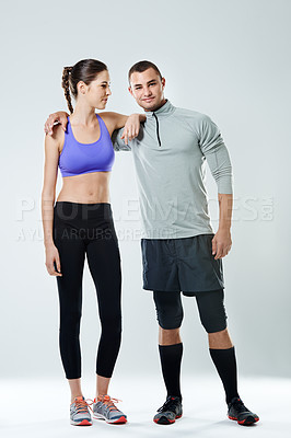 Buy stock photo Shot of a young couple standing in a studio wearing sports clothing
