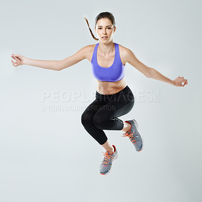 Buy stock photo A beautiful young woman in sportswear jumping against a gray background