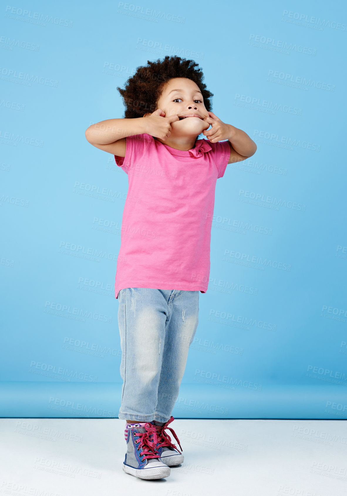 Buy stock photo Child, funny face and girl with silly, goofy facial expression on blue background in studio with fashion for children. Kid, portrait and fingers in mouth with joke, humor or emoji for crazy comedy