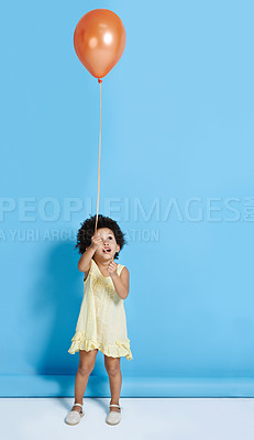 Buy stock photo Shot of a cute little girl holding a balloon over a blue background